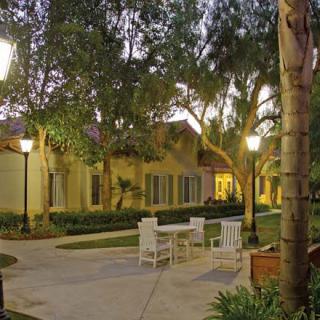 A tranquil outdoor garden setting with chairs and tables under evening lights.