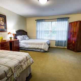A cozy bedroom with two beds, a window with curtains, and wooden furniture.