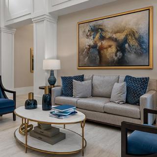 A stylish living room features a comfortable sofa, elegant armchairs, a decorative coffee table, and a striking large artwork on the wall.