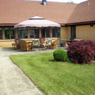 A cozy outdoor patio area with seating and a large umbrella, surrounded by a well-maintained garden.