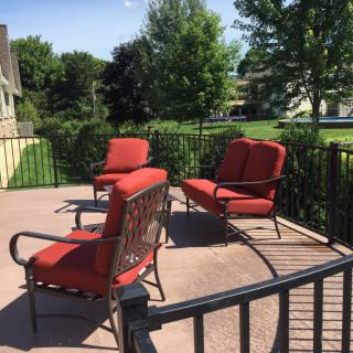 A sunny patio with red cushioned outdoor furniture.