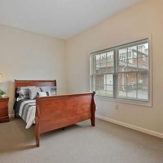 A cozy bedroom with a large window and wooden furniture.