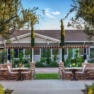 A beautiful garden setting with outdoor seating and a pergola, surrounded by lush greenery.
