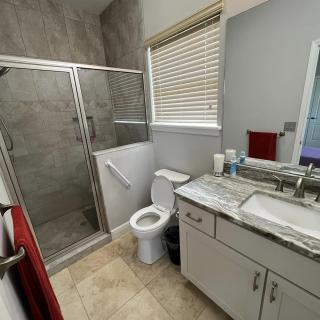 A modern bathroom with a glass shower enclosure, toilet, and a vanity with a marble countertop.