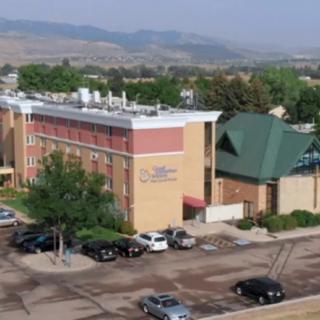 An aerial view of a building with a parking lot and surrounding landscape.
