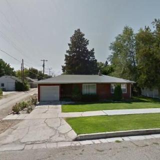 A suburban house with a well-maintained lawn and trees in the front yard.