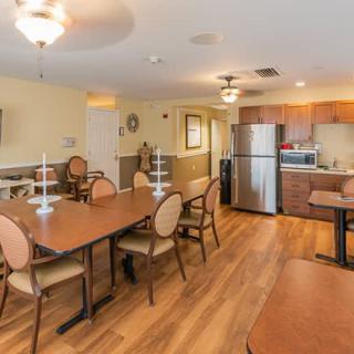 A cozy dining area with a kitchen, featuring wooden tables and chairs and modern appliances.