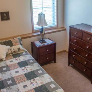 A cozy bedroom with a quilted bedspread and wooden furniture.