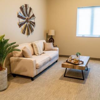 A cozy living room with a beige sofa, coffee table, and decorative elements including wall art and an indoor plant.