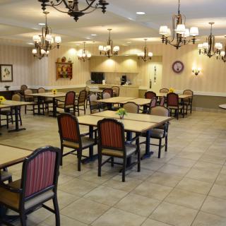 An empty dining room with arranged tables and elegant chandeliers.