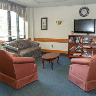 A cozy living room with seating area, television, and bookshelf.