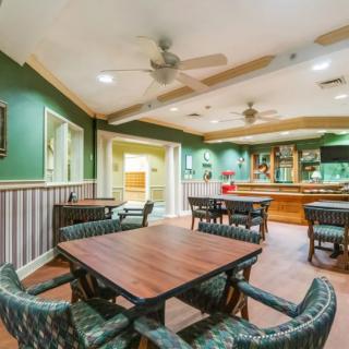 A cozy restaurant interior with a dining area featuring wooden tables and a bar in the background.