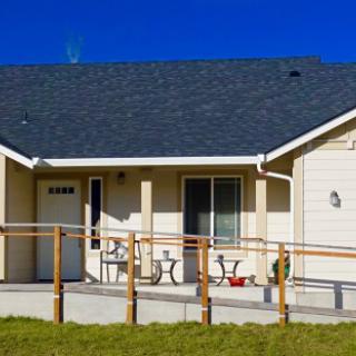 A single-story house with a ramp leading to the entrance, set against a clear blue sky.