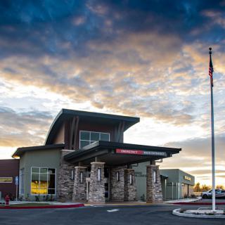 A modern building with a stone facade under a cloudy sky at sunset.