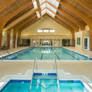 An indoor swimming pool with a spa area and vaulted wooden ceiling.
