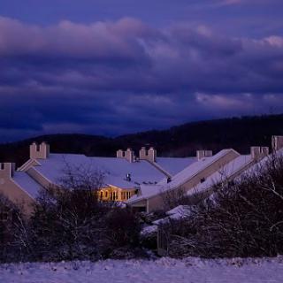 A serene winter evening view of houses blanketed in snow under a twilight sky.