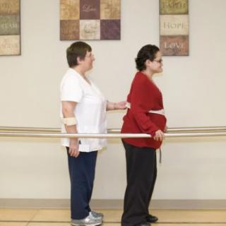 A physical therapist assists a patient with walking exercises in a rehabilitation setting.