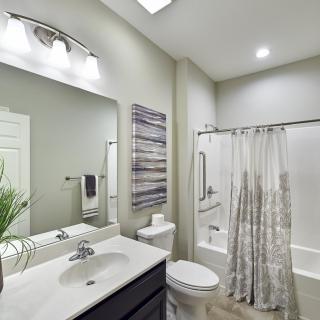 A modern bathroom with a sleek design, featuring a sink, mirror, toilet, and shower area.