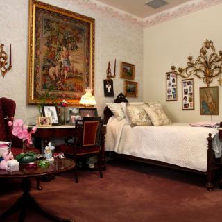A cozy bedroom with vintage decor and traditional furniture, adorned with wall art and a warm ambiance.