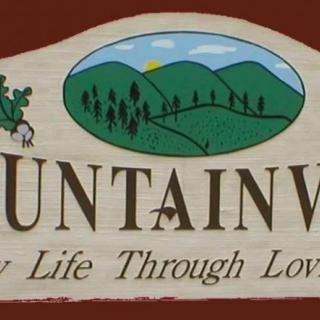 A sign displaying an illustration of mountains with a slogan beneath.