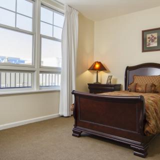 A cozy bedroom with a wooden bed and nightstand, featuring a lamp and decor.