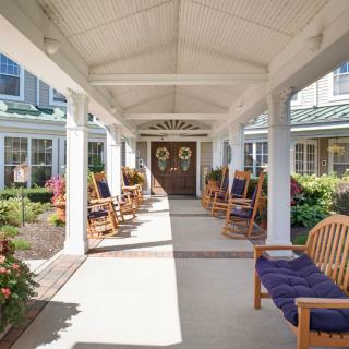 A serene porch with rocking chairs and a garden walkway leading to a house entrance.