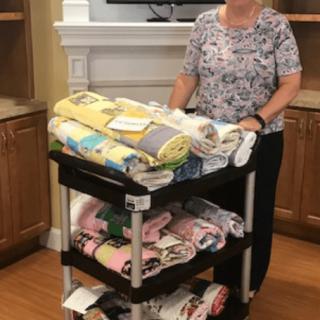 A person stands in a room next to a cart filled with quilts.