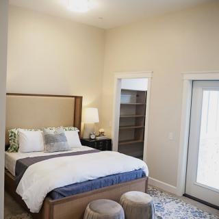 A cozy bedroom featuring a neatly made bed with decorative pillows, a bedside lamp, and an area rug.