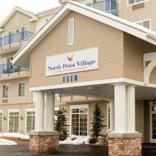 The entrance of North Hill Village with a prominent sign and snowy surroundings.