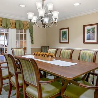 A well-appointed dining room with a long table, elegant chairs, and a chandelier.