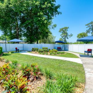 A serene garden patio with outdoor seating and well-maintained landscaping under a clear blue sky.