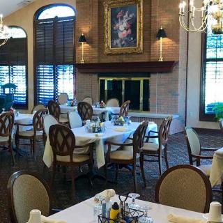 A cozy dining area with elegantly set tables, a fireplace, and decorative artwork.
