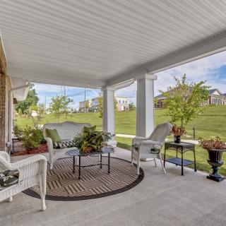 A cozy porch with elegant wicker furniture and a scenic garden view.