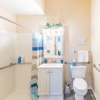 A well-lit bathroom with a shower, sink, and toilet.