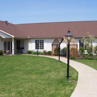 A single-story house with a well-maintained lawn and pathway lined with lamp posts.