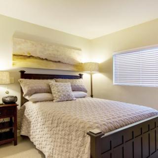 A cozy bedroom with a neatly made bed, side tables, and soft lighting.