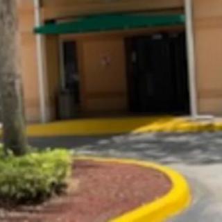 A building entrance with a green awning and surrounding landscaping.