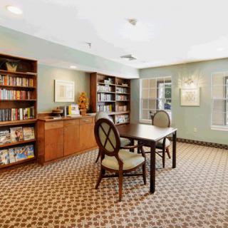 A cozy reading room with bookshelves, a table, and chairs.