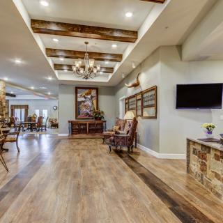 A spacious and elegantly designed living area featuring wooden flooring, a chandelier, comfortable seating, and modern decor.
