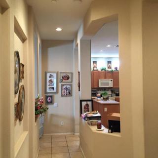 A view down a hallway leading to a kitchen, with artwork and decorations on the walls.