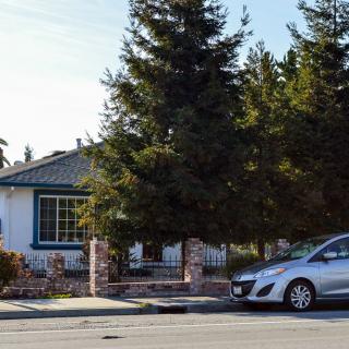 A suburban house with a car parked on the street in front.