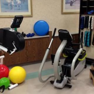 A gym with various exercise equipment, including an elliptical machine and colorful fitness balls.