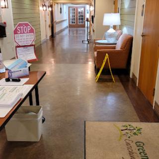A well-lit hallway featuring a seating area, caution sign, and informational materials.