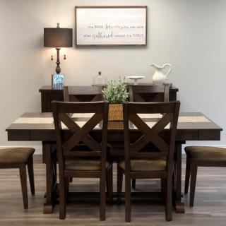 A cozy dining room setup with a wooden table and chairs, accented by a lamp and wall decor.