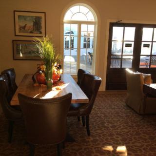 A cozy dining room with a wooden table and chairs, beautifully lit by sunlight.