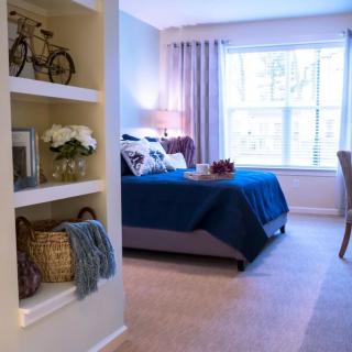 A cozy bedroom with decorative shelves and a large window letting in natural light.