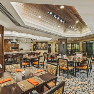A modern and elegant restaurant dining area with neatly arranged tables and a wooden ceiling.