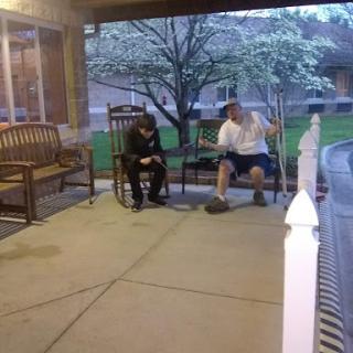 Two individuals seated on a porch enjoying a conversation in the evening.