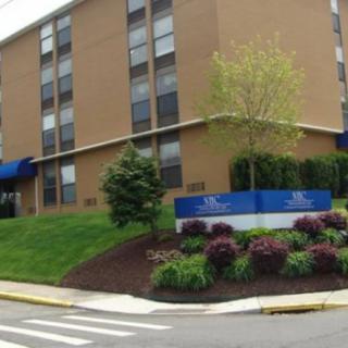 A multi-story apartment building with well-maintained landscaping and a blue sign at the entrance.