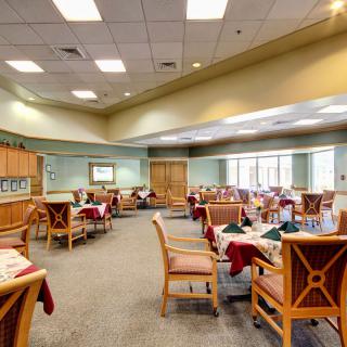 A spacious dining room with neatly arranged tables and chairs, featuring elegant table settings and bright ceiling lights.